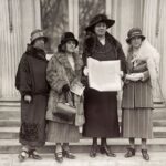 Ffotograff du a gwyn o Annie Hughes Griffiths sy’n cynnal apêl heddwch y merched y tu allan i’r Tŷ Gwyn yn Washington yn dilyn eu cyfarfod â’r Llywydd Calvin Coolidge yn 1924, ochr yn ochr â (L-R)Gladys Thomas, Mary Ellis ac Elined Prys