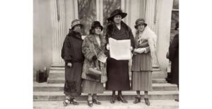 Ffotograff du a gwyn o Annie Hughes Griffiths sy’n cynnal apêl heddwch y merched y tu allan i’r Tŷ Gwyn yn Washington yn dilyn eu cyfarfod â’r Llywydd Calvin Coolidge yn 1924, ochr yn ochr â (L-R)Gladys Thomas, Mary Ellis ac Elined Prys