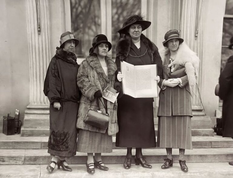 Ffotograff du a gwyn o Annie Hughes Griffiths sy’n cynnal apêl heddwch y merched y tu allan i’r Tŷ Gwyn yn Washington yn dilyn eu cyfarfod â’r Llywydd Calvin Coolidge yn 1924, ochr yn ochr â (L-R)Gladys Thomas, Mary Ellis ac Elined Prys